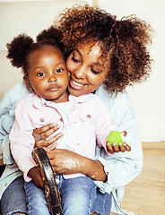 Image showing adorable sweet young afro-american mother with cute little daughter, hanging at home, having fun playing smiling, lifestyle people concept