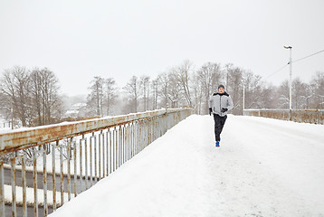 Image showing man running along snow covered winter bridge road