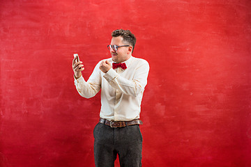 Image showing Portrait of puzzled man talking by phone a red background