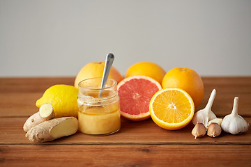 Image showing honey, citrus fruits, ginger and garlic on wood