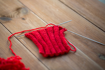Image showing hand-knitted item with knitting needles on wood