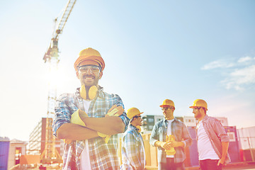 Image showing group of smiling builders in hardhats outdoors