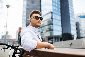 Image showing happy young man with bicycle sitting on city bench