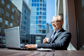 Image showing senior businessman with laptop drinking coffee