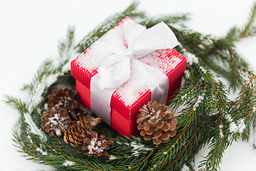 Image showing christmas gift and fir wreath with cones on snow