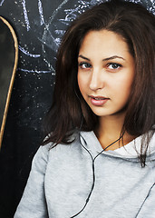 Image showing young cute teenage girl in classroom at blackboard seating on ta