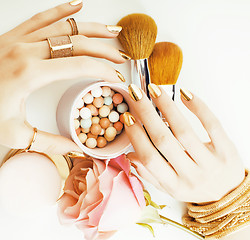 Image showing woman hands with golden manicure and many rings holding brushes,