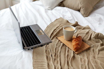 Image showing laptop, coffee and croissant on bed at cozy home