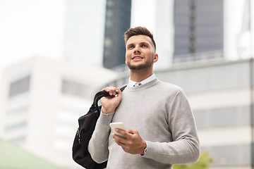Image showing happy young man with smartphone and bag in city
