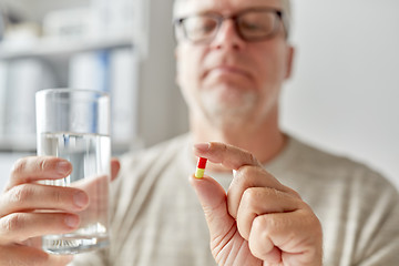 Image showing close up of old man hands with pill and water