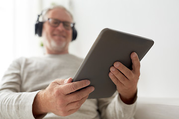 Image showing senior man with tablet pc and headphones at home