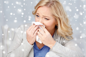 Image showing ill woman blowing nose to paper napkin