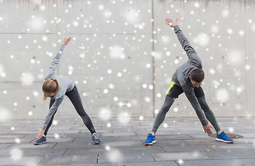 Image showing couple of sportsmen stretching on city street