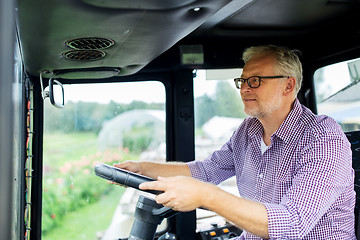 Image showing senior man driving tractor at farm