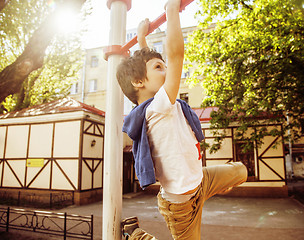 Image showing little cute blond boy hanging on playground outside, alone training with fun, lifestyle children concept