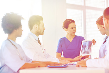 Image showing group of doctors with x-ray on tablet pc at clinic