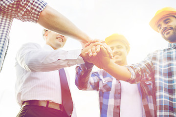 Image showing close up of builders in hardhats with hands on top