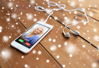 Image showing close up of smartphone and earphones on wood