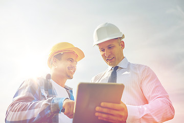 Image showing happy builders in hardhats with tablet pc outdoors