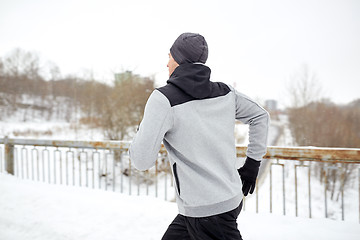 Image showing man running along snow covered winter bridge road