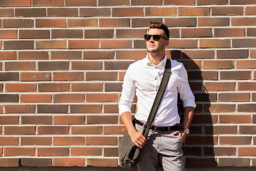 Image showing young man in sunglasses with bag over brickwall