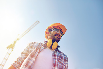 Image showing smiling builder with hardhat and headphones