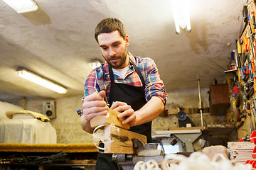 Image showing carpenter working with plane and wood at workshop