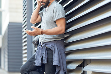 Image showing man with earphones, smartphone and bag on street