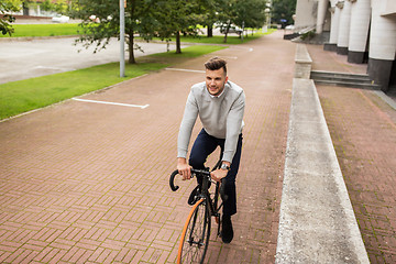 Image showing young man riding bicycle on city street