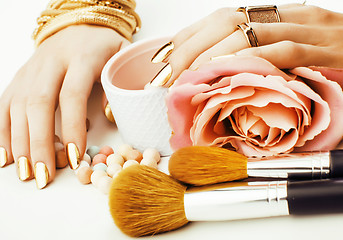 Image showing woman hands with golden manicure and many rings holding brushes,