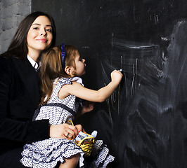 Image showing portrait of mature woman teacher with little cute blonde girl pupil writing on blackboard together, lifestyle people concept