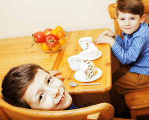 Image showing little cute boys eating dessert on wooden kitchen. home interior