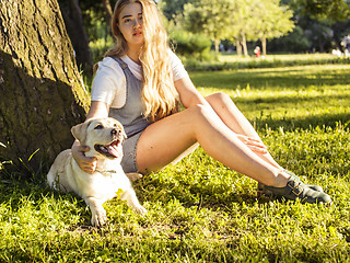 Image showing young attractive blond woman playing with her dog in green park at summer, lifestyle people concept