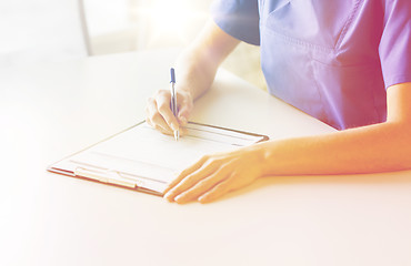 Image showing close up of doctor or nurse writing to clipboard