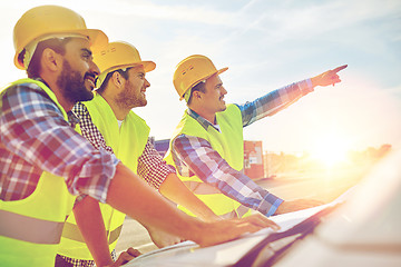 Image showing close up of builders with blueprint on car hood