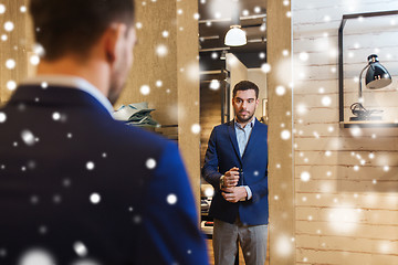 Image showing man trying jacket on at mirror in clothing store