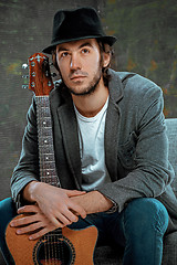 Image showing Cool guy sitting with guitar on gray background
