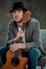 Image showing Cool guy sitting with guitar on gray background