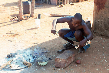 Image showing Himba man adjusts wooden souvenirs