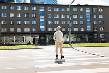 Image showing senior man walking along city crosswalk