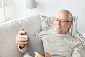 Image showing senior man with tablet pc lying on sofa at home