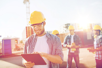 Image showing smiling builders in hardhats with tablet pc