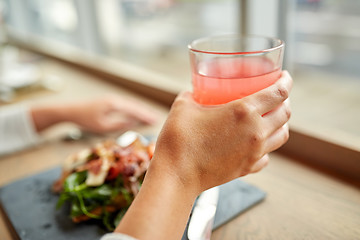Image showing hand with glass of juice and salad at restaurant
