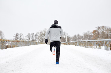 Image showing man running along snow covered winter bridge road