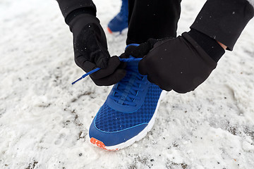 Image showing close up of man tying shoe lace in winter outdoors