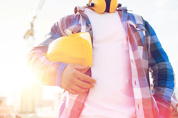 Image showing close up of builder holding hardhat on building