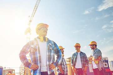 Image showing group of smiling builders in hardhats outdoors