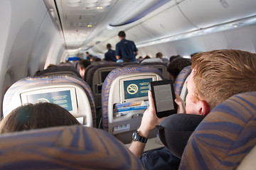 Image showing Male passenger reading e-book on electronic reader on airplane.