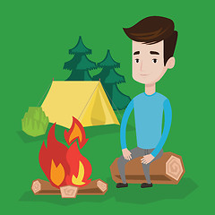 Image showing Man sitting on log near campfire in the camping.