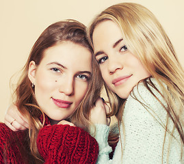 Image showing Two young girlfriends in winter sweaters indoors having fun. Lifestyle. Blond teen friends close up